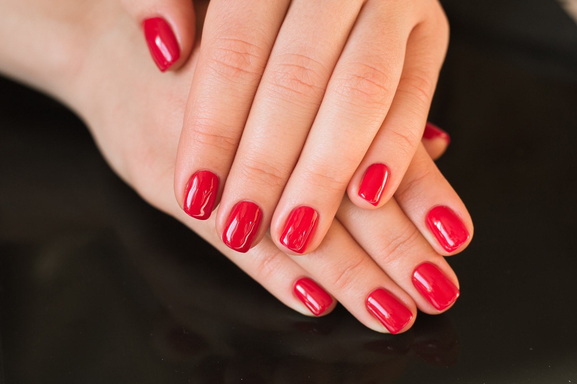 red manicure with nail on a black background
